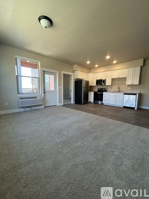 A spacious living room with a kitchen in the background.