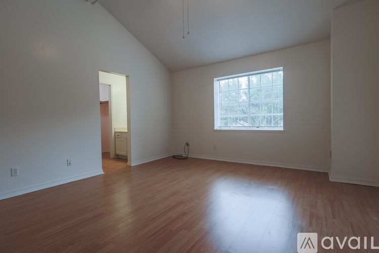 A room with wooden floors and a window with a view of trees.