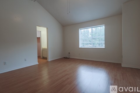 A room with wooden floors and a window with a view of trees.