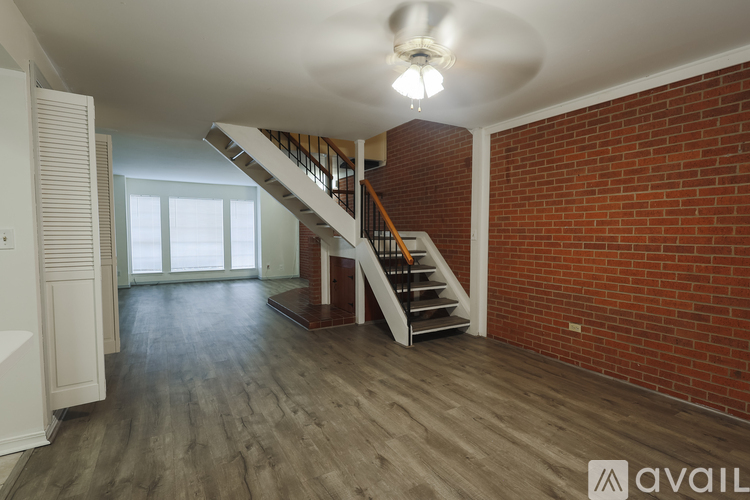 A spacious room with a staircase and brick wall.
