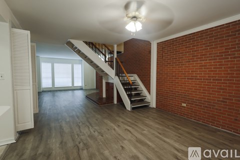 A spacious room with a staircase and brick wall.