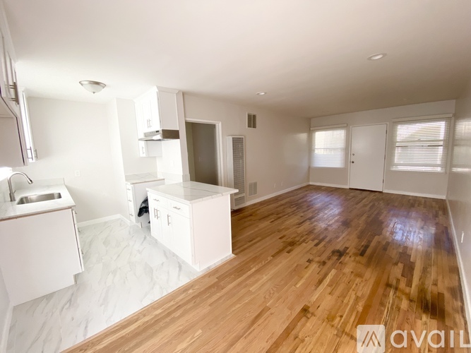 A spacious room with wooden flooring and white walls.
