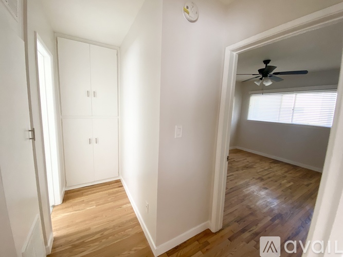 A kitchen with a fan on the ceiling and a window with a view of trees.