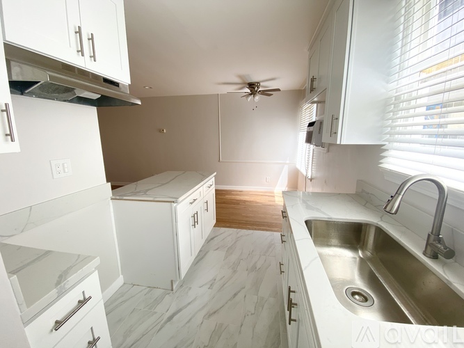 A spacious room with wooden flooring and a large window.