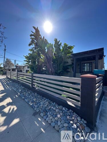 A sunny day with a wooden fence and a building in the background.