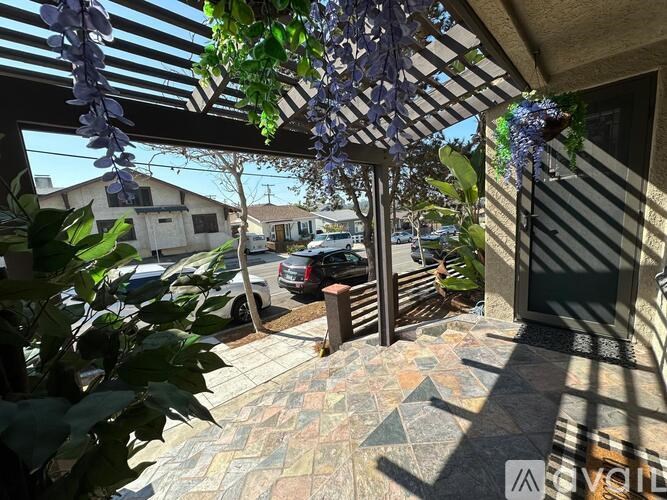 A patio with a tiled floor and a pergola with purple flowers.