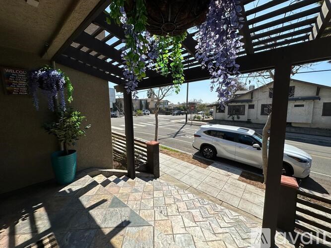 A white car is parked on the street in front of a house.