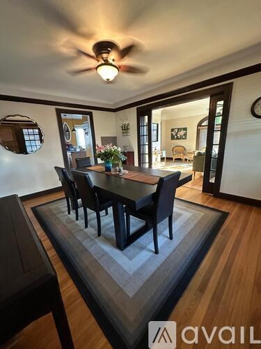 A dining room with a table and chairs and a fan on the ceiling.