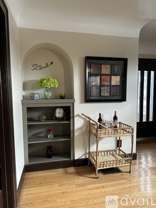 A shelf with a vase of flowers and a bottle of wine on it.