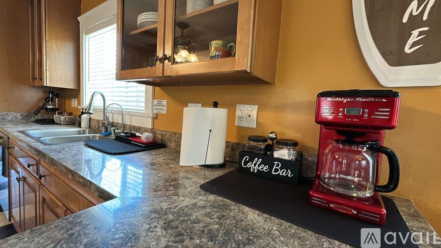 A kitchen with a red coffee maker on a black tray.