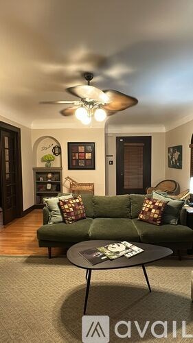 A living room with a green couch and a ceiling fan.