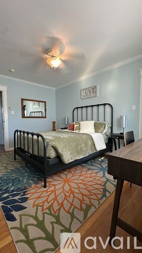 A bedroom with a bed, a rug, and a mirror on the wall.