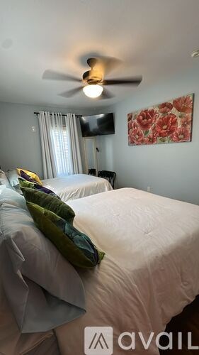 A bedroom with a bed, a ceiling fan, and a television.