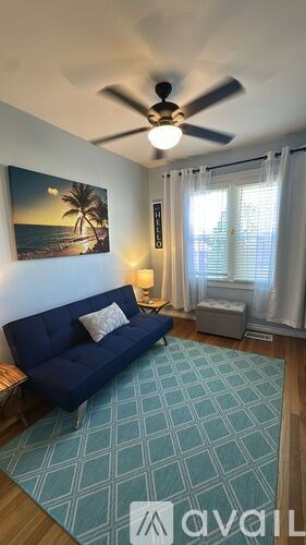 A living room with a blue couch and a ceiling fan.