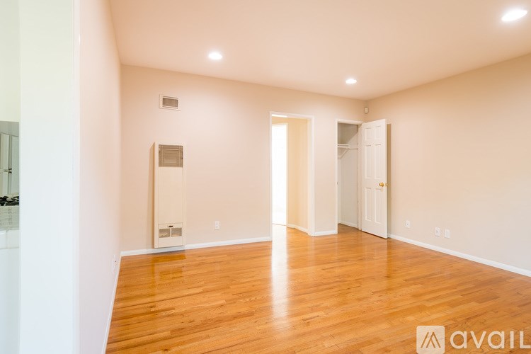 A room with wooden floors and white walls, with a door on the right side.