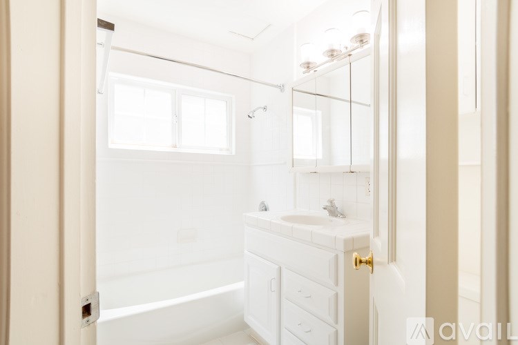A white bathroom with a tub, sink, and mirror.