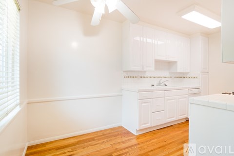 A kitchen with white cabinets and a wooden floor.