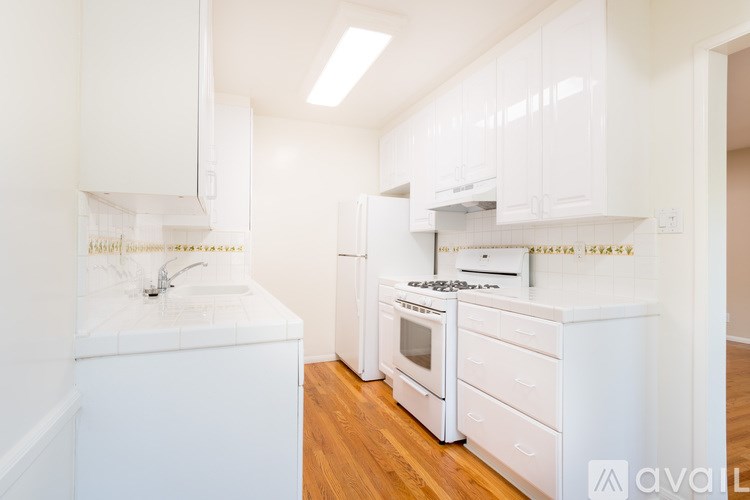 A white kitchen with wooden floors and white appliances.