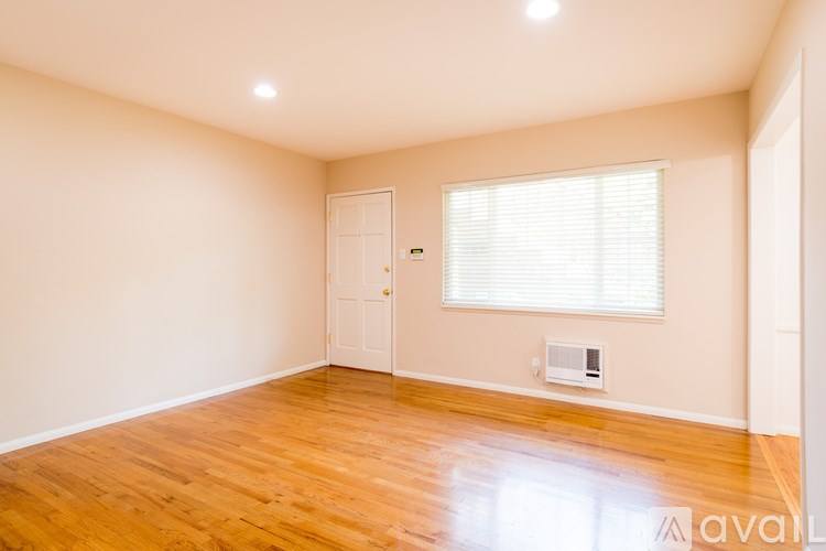A room with wooden floors and a window with blinds.