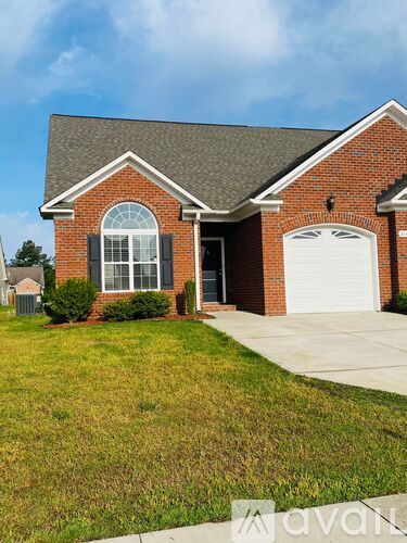 A brick house with a white car parked in front.
