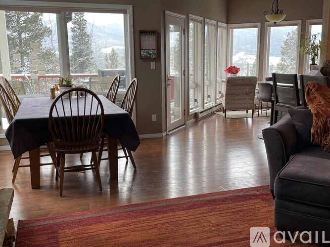 A dining room with a table set for six and a view of the outdoors.
