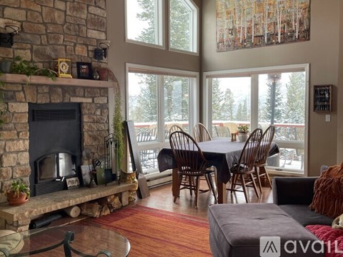 A living room with a stone fireplace and a dining table set up.