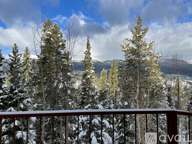 A snowy landscape with trees and mountains in the distance.
