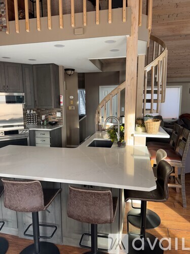 A kitchen with a table and chairs in the foreground and a staircase in the background.
