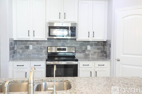 A kitchen with white cabinets and a black oven.