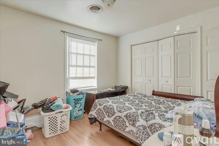 A bedroom with a bed, a window with blinds, and a fan on the ceiling.