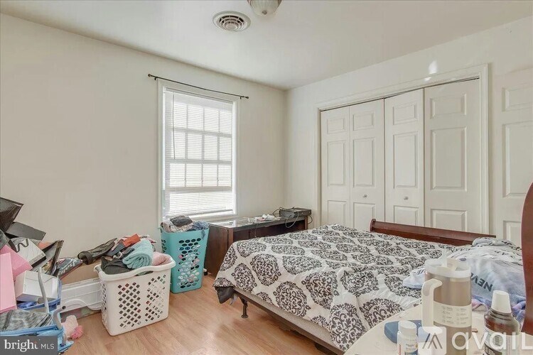 A bedroom with a bed, a window with blinds, and a fan on the ceiling.