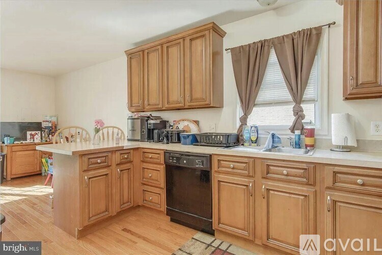 A kitchen with wooden cabinets and a black dishwasher.