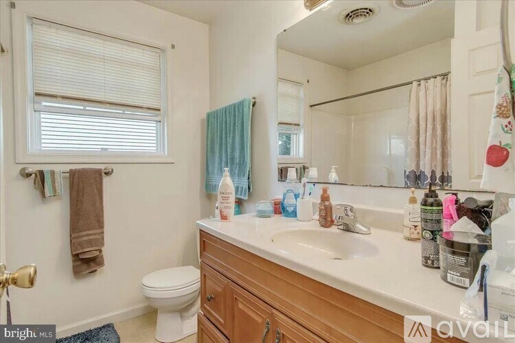 A bathroom with a toilet, sink, and mirror.