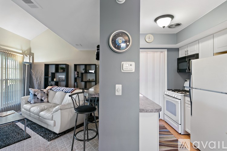 A modern kitchen with a white refrigerator and a dining area with a white couch and a black stool.