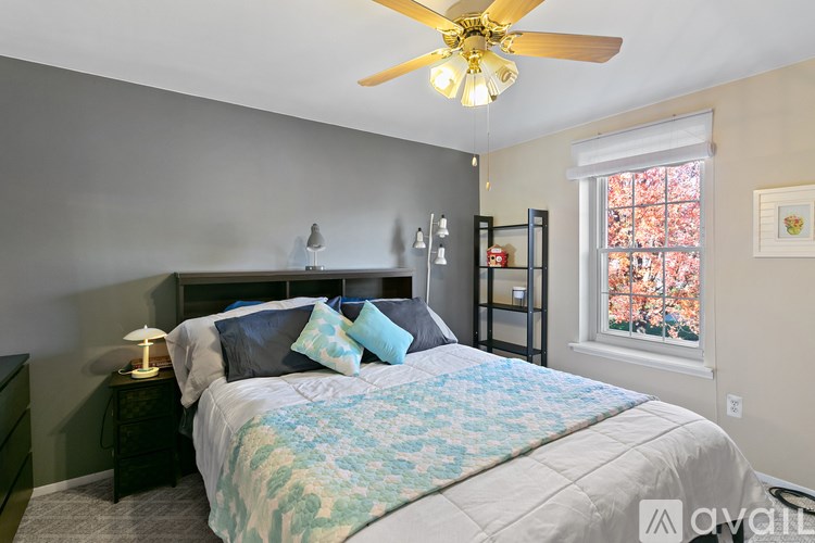 A bedroom with a bed, a ceiling fan, and a window with a view of trees outside.