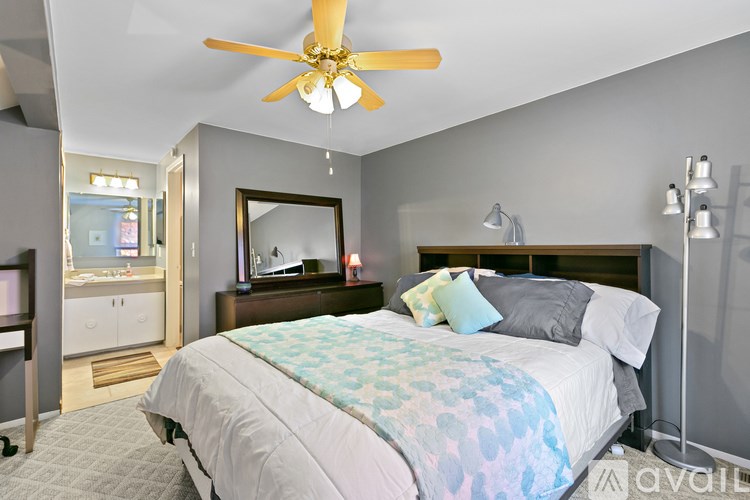 A bedroom with a bed, dresser, mirror, and ceiling fan.