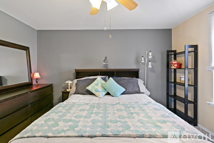 A bedroom with a bed, nightstand, and a mirror on the wall.