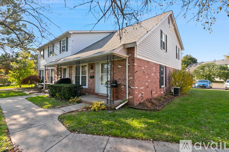 A house with a white front porch and a brick wall.
