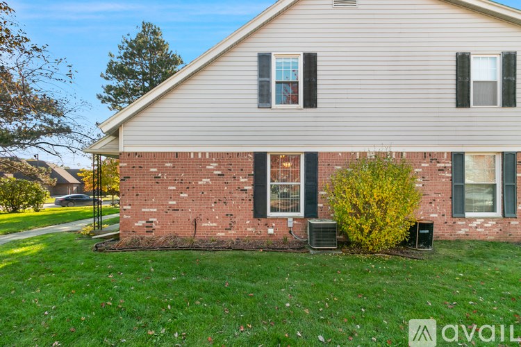 A house with a brick wall and a window with black shutters.