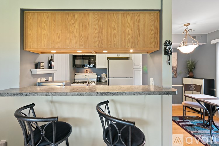 A kitchen with a granite countertop and two black chairs.