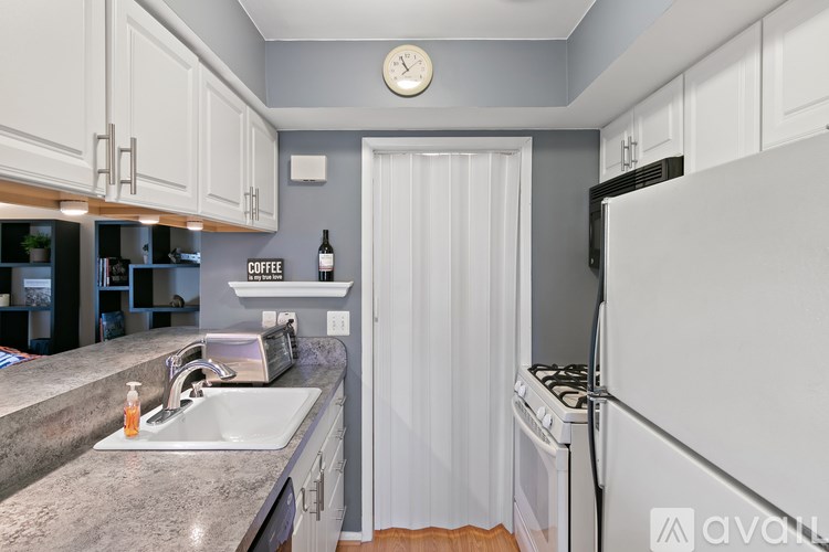 A kitchen with a white refrigerator, sink, and cabinets.