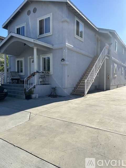 A two-story house with a white exterior and a balcony on the second floor.