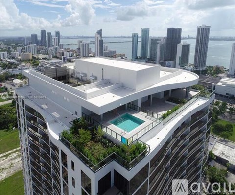 A modern building with a pool on the top floor overlooks a cityscape.