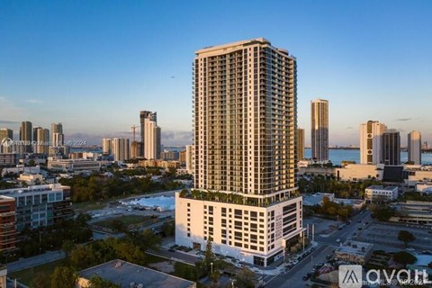 A tall white building with balconies is the focal point of a cityscape.