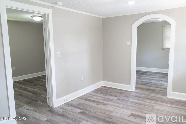 A room with a grey floor and white walls with a doorway leading to another room.