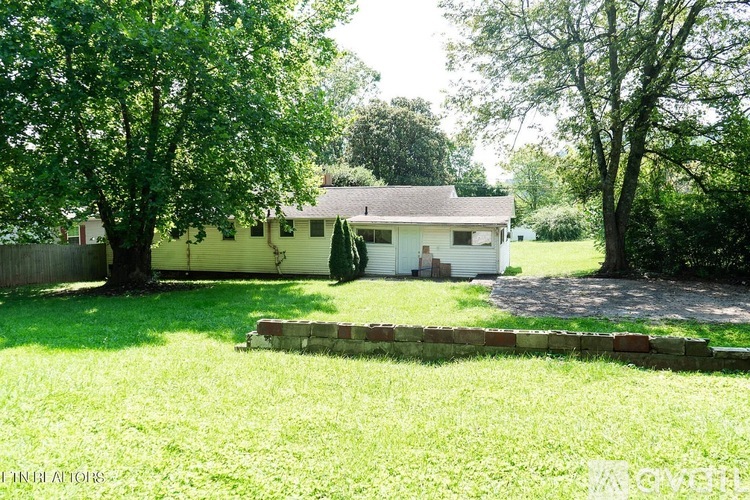 A house with a white garage door is surrounded by a grassy yard.