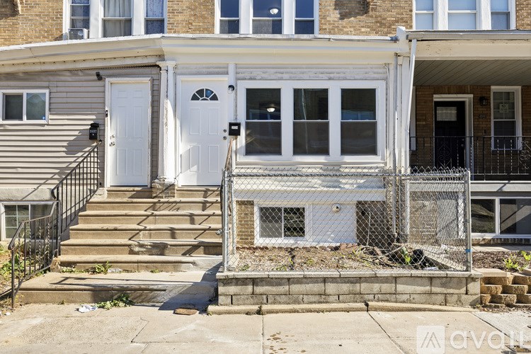 A white door with a black railing in front of a brown building.