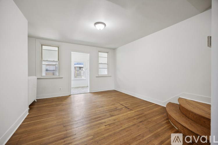 A room with wooden floors and a staircase leading to another room.