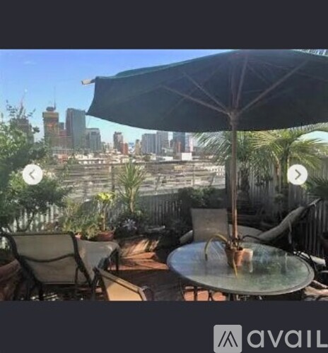 A patio with a table, chairs, and an umbrella overlooking a city skyline.