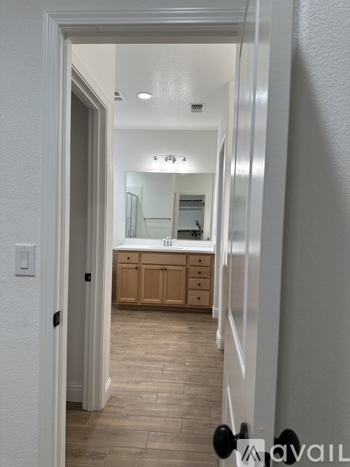 A hallway with a mirror and wooden cabinets.